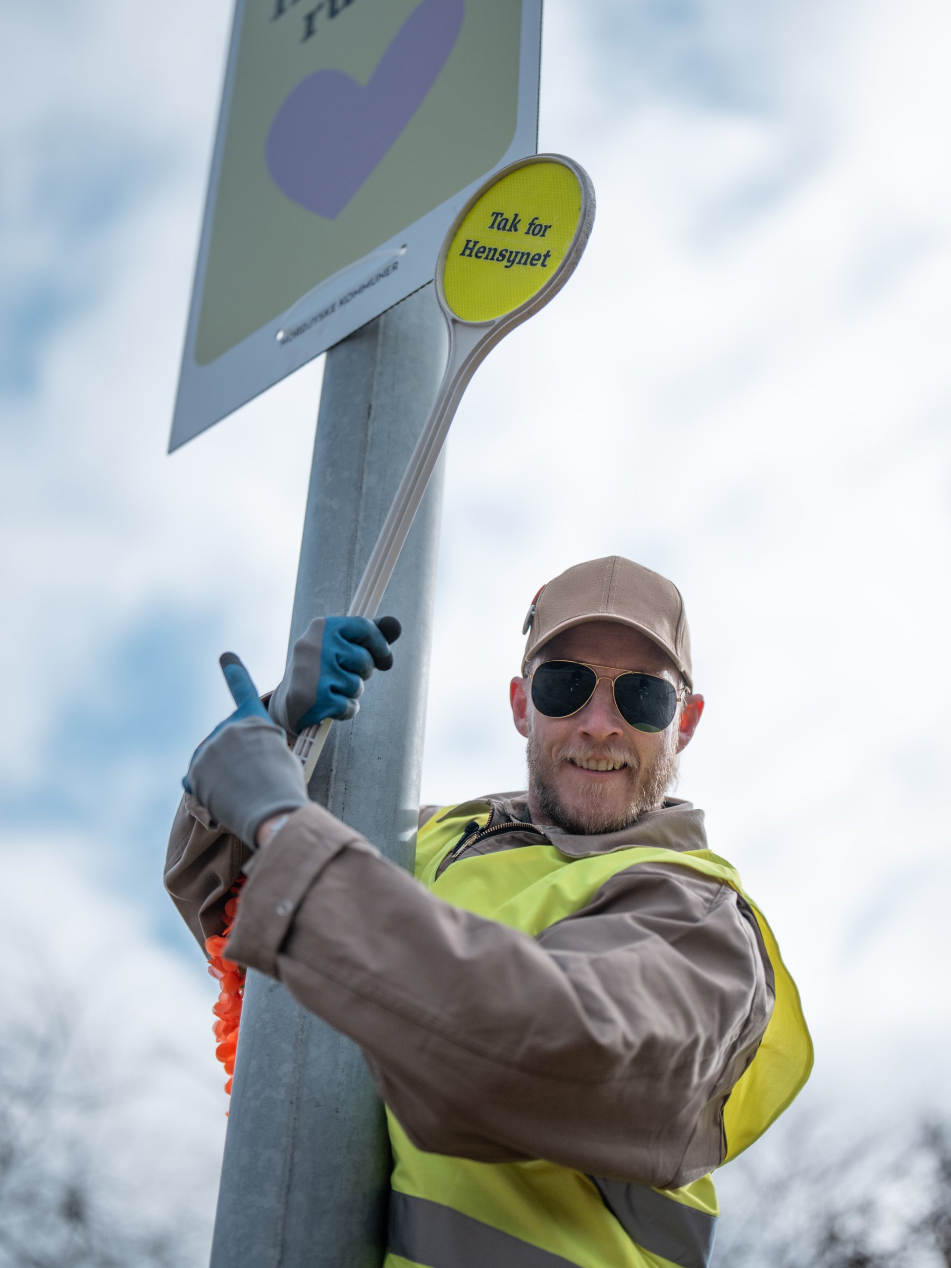 Søren Vige der står ved en lygtepæl med en 'Hensynes ruten' plakat på.