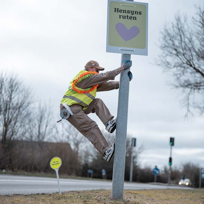 Søren Vige der kravler i lygtepæl for at hænge 'Hensyns ruten' plakat op.